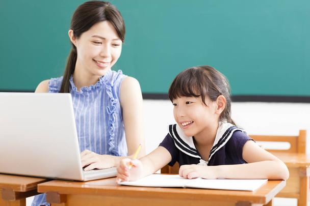 Молодой учитель помогает ребенку с компьютерным уроком
 - Фото, изображение