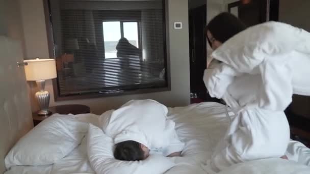 Verliefde paar in witte jassen op bed gelukkig gevechten met kussens slowmotion stock footage video - Video