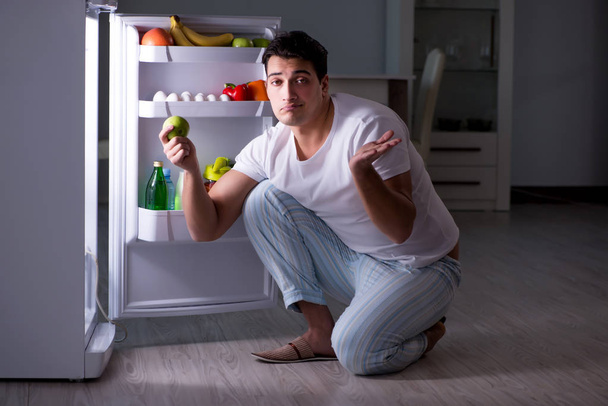 Чоловік в холодильнику їсть вночі
 - Фото, зображення
