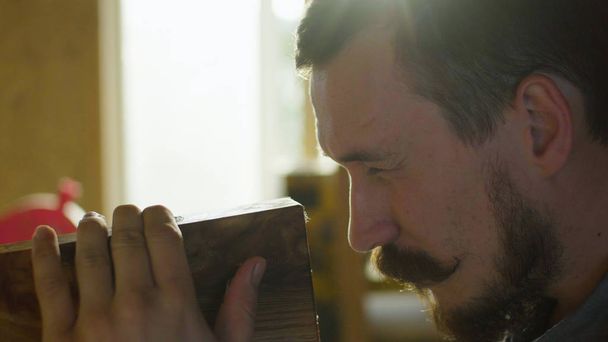 Portrait of concentrated woodworker rubs lacquer in a wooden plank in workshop - Foto, immagini
