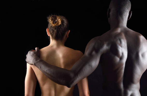 黒い背景に異人種間のカップルの抱擁 - 写真・画像