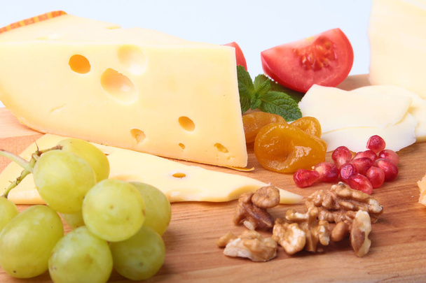 Assortment of cheese with fruits, grapes, nuts and cheese knife on a wooden serving tray. - Fotografie, Obrázek