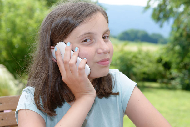 lachende pre tiener meisje bellen op smartphone, buiten - Foto, afbeelding