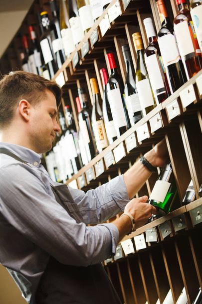 Thoughtful expert in winemaking on background of shelves with wine. - Foto, Bild