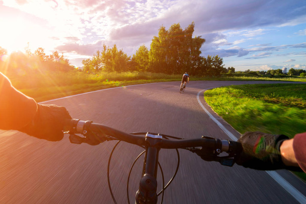 Riding a bike first person perspective. Olympic bicycle road towards sun. - Foto, Imagen