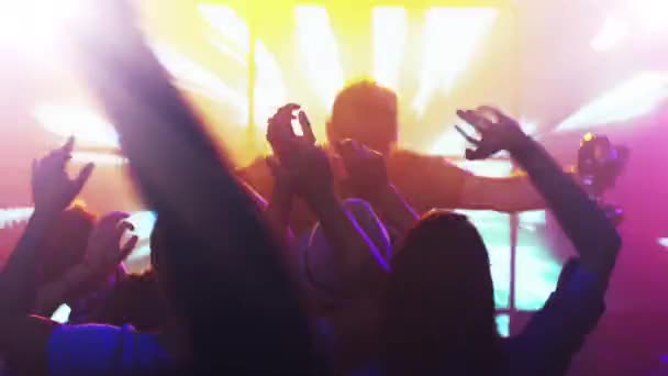 DJ играет музыку в ночном клубе, люди танцуют, веселятся и поднимают руки
. - Кадры, видео