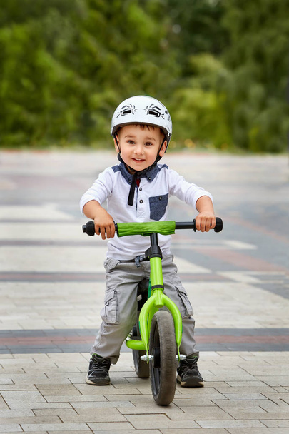 Child boy in white helmet riding on his first bike with a helmet. Bike without pedals. - Фото, зображення