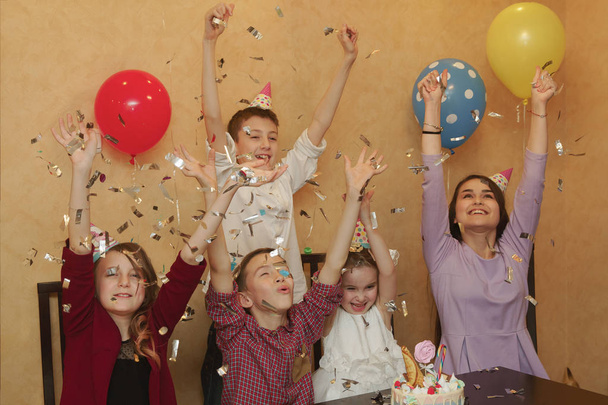 Группа детей в праздничных шапках на детской вечеринке. Дети веселятся вместе на семейном празднике
. - Фото, изображение