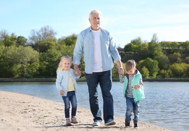 Dziadek z dziećmi na brzegu rzeki - Zdjęcie, obraz