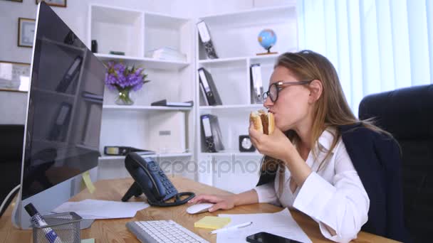 Busy woman talking on the phone while having burger - Video, Çekim