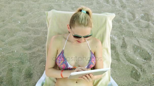 Όμορφη γυναίκα σε ένα μαγιό με έναν υπολογιστή tablet. Νεαρή γυναίκα με ένα tablet στην παραλία. Κορίτσι στο μπικίνι με tablet. - Πλάνα, βίντεο