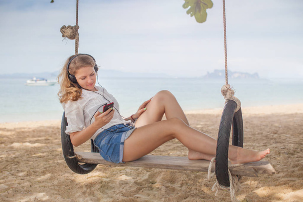Girl sitting on the swing on the tropical beach, paradise island - Foto, Imagem