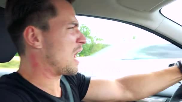 man rijdt een auto en scheldt achter het stuur - Video