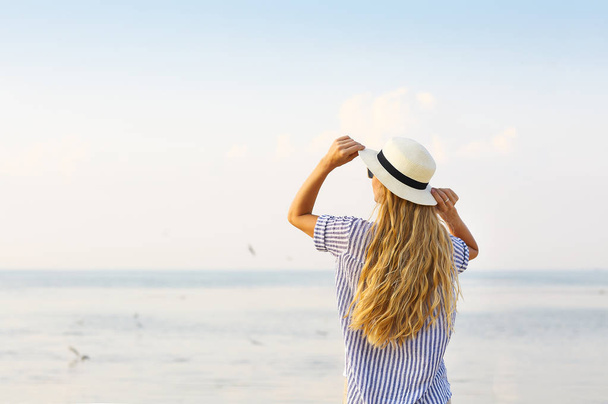 Donna sulla spiaggia con il cappello bianco
  - Foto, immagini