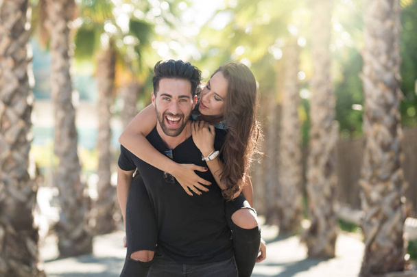 Young happy man giving his girlfriend a piggyback ride - Foto, imagen