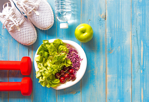 Healthy lifestyle sport equipment fitness, sneakers, green apple, fresh water and healthy food on blue wood background.  Healthy Concept. - Foto, Imagen