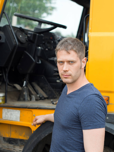 Чоловік вантажівка стоїть біля своєї жовтої вантажівки
. - Фото, зображення