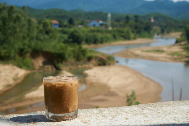 Eiskaffee oder Caffe Latte vor einer netten verschwommenen Landschaft in Vietnam, Phong Nhake Bang Nationalpark. - Foto, Bild
