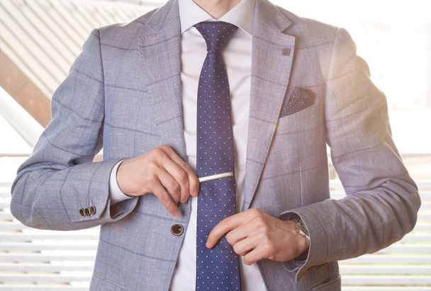 Homme d'affaires méconnaissable mettre la cravate droite en ajustant son épingle à cravate. Rétro-éclairage avec effet de fusée éclairante
. - Photo, image