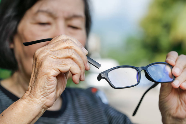 Літня азіатка ремонтує зламані окуляри
 - Фото, зображення