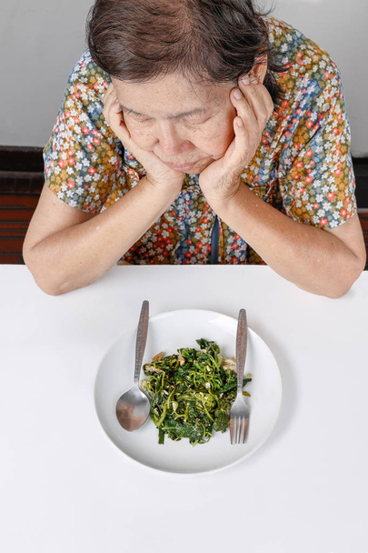 Oudere Aziatische vrouw verveeld met voedsel - Foto, afbeelding