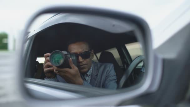 Reflection in side mirror of Paparazzi man sitting inside car and photographing with dslr camera - Felvétel, videó