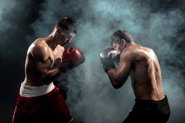 Two professional boxer boxing on black smoky background, - Foto, immagini