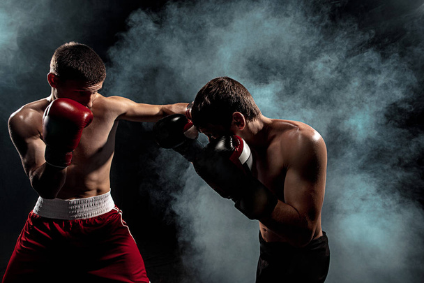 Two professional boxer boxing on black smoky background, - Фото, изображение