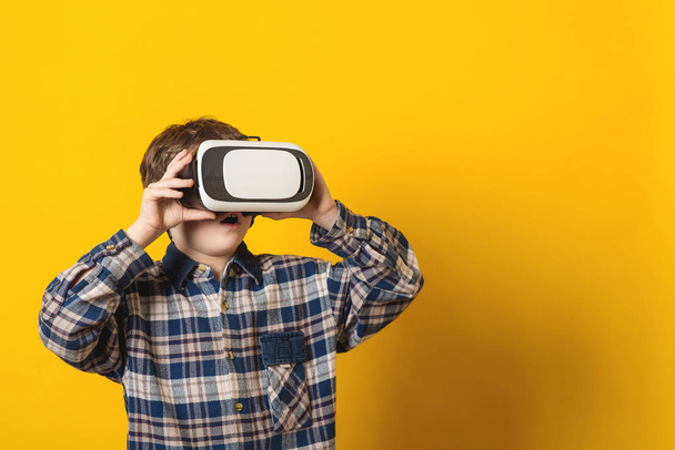 Хлопчик в окулярах віртуальної реальності на жовтому фоні
. - Фото, зображення