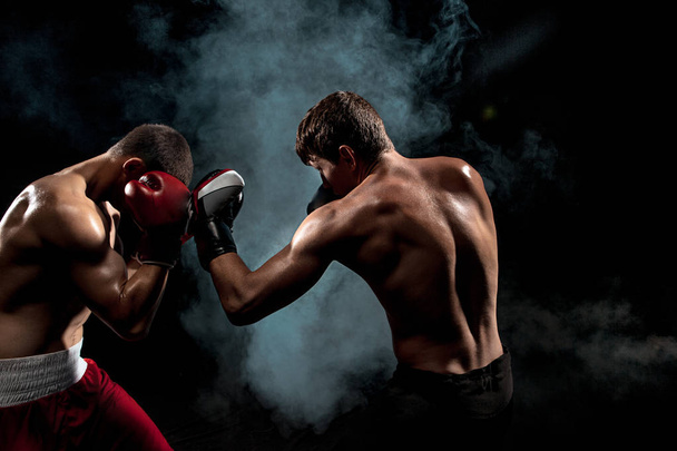 Two professional boxer boxing on black smoky background, - Foto, Imagen