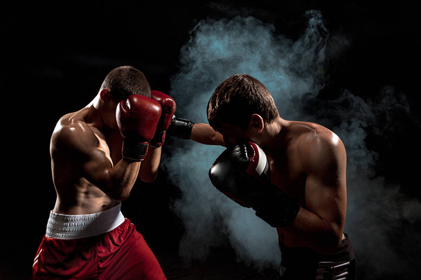 Two professional boxer boxing on black smoky background, - Фото, зображення