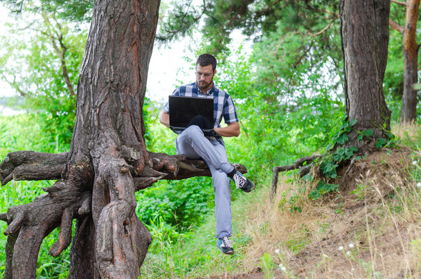 A fiatalember ellazítja laptop ül a parkban, a munka és a r - Fotó, kép