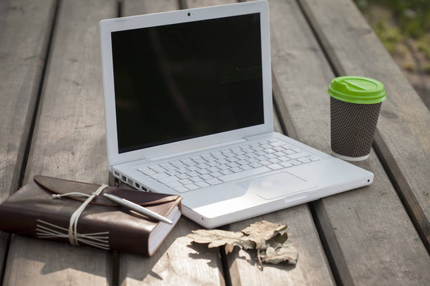 Laptop na drewnianym molo, w pobliżu wody. Świetne miejsce do pracy lub zabawy, szczególnie w okresie letnim. Notatnik i kawa - Zdjęcie, obraz