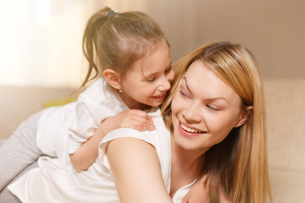 Mamá y su linda hija niña están jugando, sonriendo y abrazándose. Feliz día de la madre
. - Foto, Imagen