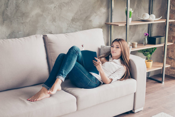 Serious young lady is studying, lying on the cozy couch in livin - Foto, imagen