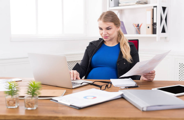 Pregnant business lady at work reading papers - Photo, Image