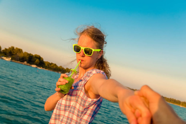 Beautiful female holding man's hand and drinking fresh kiwi juic - Photo, Image