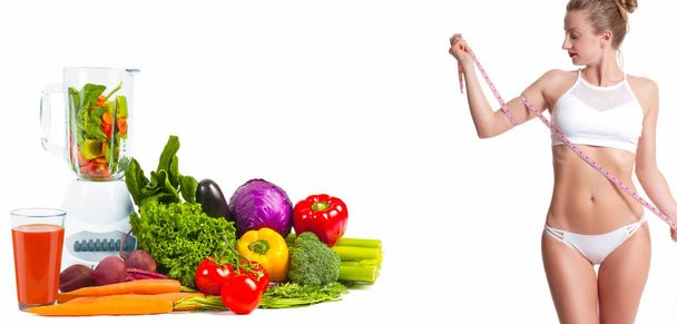 Uma mulher a medir o corpo com uma fita métrica. Conceito de dieta, legumes frescos
 - Foto, Imagem