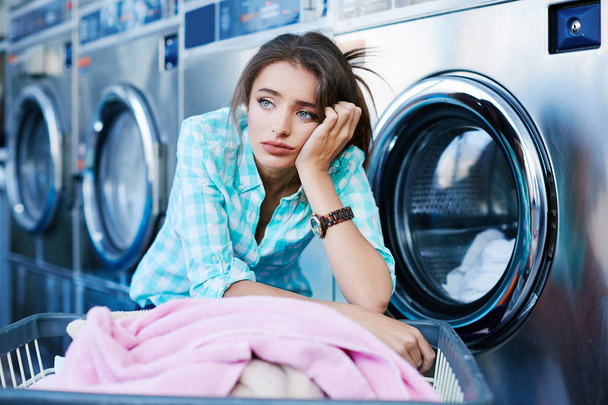 Mujer aburrida cerca de lavadoras
 - Foto, Imagen
