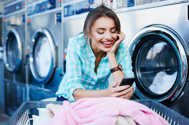Mädchen benutzt App zum Wäschewaschen - Foto, Bild