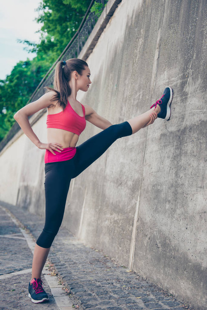 Pretty young slim trainer is stretching her legs by doing exerci - Photo, Image