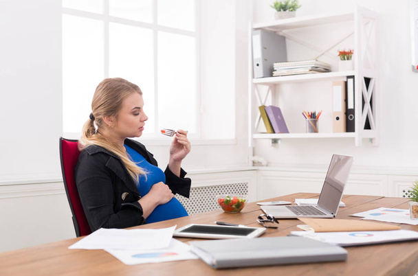 Femme d'affaires enceinte mangeant de la salade au bureau
 - Photo, image