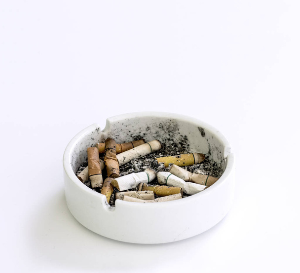 Окурки сигарет в пепельнице на белом фоне
 - Фото, изображение
