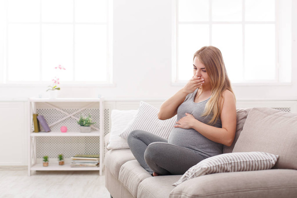 Young vomiting woman sitting on sofa - Photo, Image