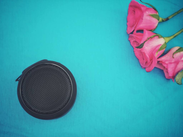 Bluetooth speaker and pink rose on blue background - Photo, Image