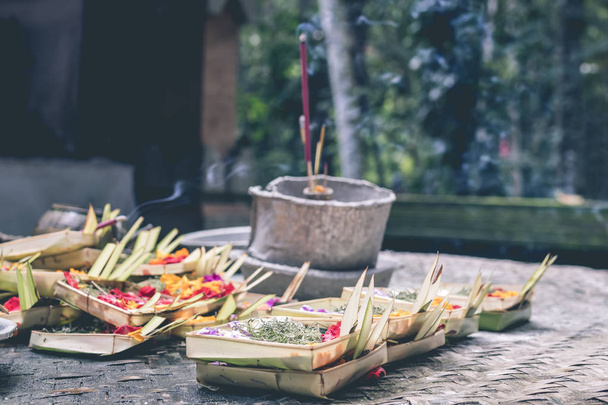 Traditional balinese offerings to gods in Bali with flowers and aromatic sticks. Bali island. - Photo, Image