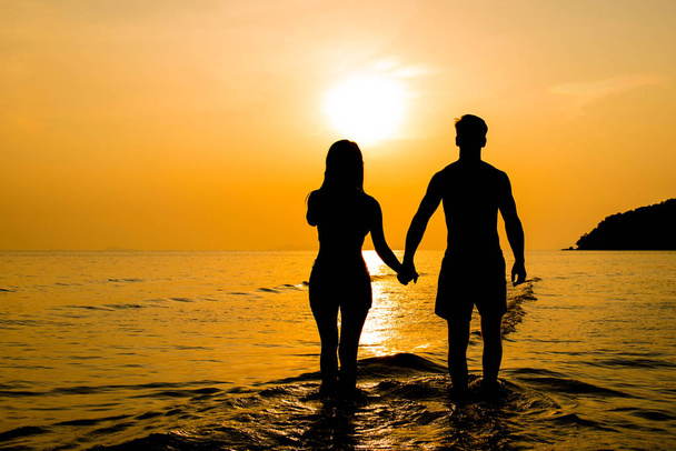 Silhouette eines Paares am Strand bei Sonnenuntergang - Foto, Bild
