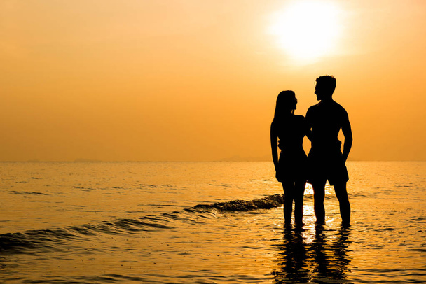 Silhueta de casal encantador na praia ao pôr do sol
 - Foto, Imagem