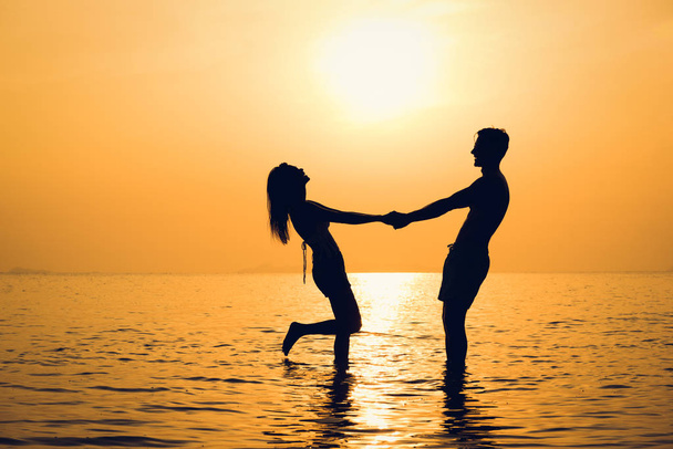 Silhouette von glücklichen schönen Paar Händchen haltend am Strand im Sonnenuntergang - Foto, Bild
