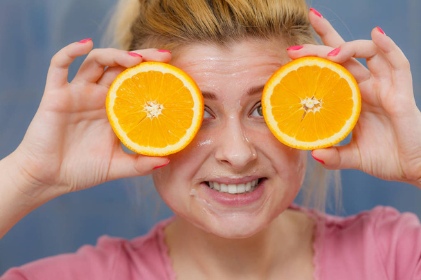 Woman having gel mask on face holding orange - Фото, зображення